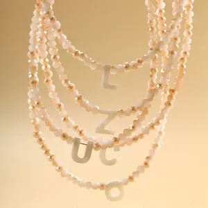 Vue détaillée du collier de perles multicouches avec pendentifs lettres en coquillage bohème.