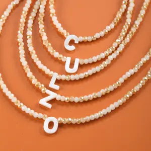 Collier superposé avec pendentif lettre en coquillage et fins détails de perles