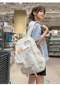 Vista detallada de una linda mochila blanca con bordado de lazos usada en una tienda