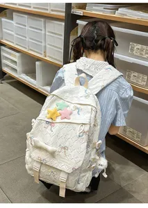 Mochila blanca acolchada con bordados de lazos y amuletos de estrellas de felpa