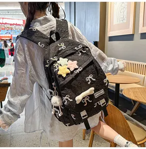 Primer plano de una mochila escolar negra con bordado de lazos y adornos de estrellas