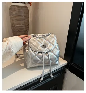 Nahaufnahme eines silbernen gesteppten Rucksacks mit Kettenriemen und Metallic-Finish