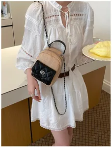 Close-up of a women's summer straw backpack with a black quilted pocket and chain strap