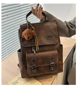 Vista dettagliata di uno zaino vintage in pelle PU marrone con un ciondolo a forma di orso