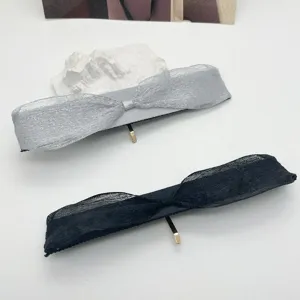 Gros plan détaillé de deux barrettes à nœud en tissu gris et noir avec crochets dorés