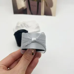 Vue détaillée d'une pince à cheveux à nœud gris clair avec ruban élégant et texture voile.