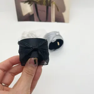 Vue détaillée d'un accessoire de manchette de cheveux à nœud en dentelle noire tenu à la main