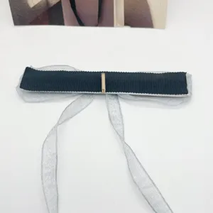 Détail en gros plan d'une pince à cheveux avec ruban noir et tissu en organza bleu