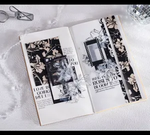 Detailansicht von schwarz-weißem Blumen-Washi-Tape und dekorativen Aufklebern im Notizbuch