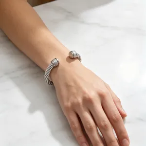 Vue de détail d'un bracelet manchette ouvert torsadé en acier titane avec des embouts en losange.