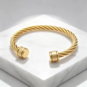 Bracelet jonc ouvert torsadé en acier inoxydable doré avec détails embouts losanges.