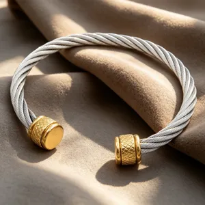 Vue détaillée d'un bracelet manchette en câble torsadé avec des embouts texturés dorés.