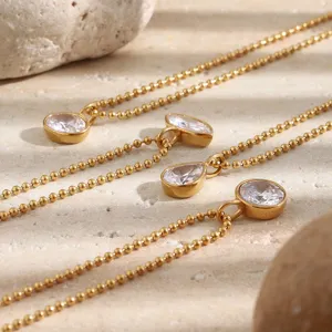 Detailed view of gold bead chain necklaces featuring round and teardrop zircon pendants