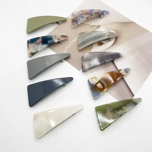 Assorted marble pattern and solid color geometric resin hair clips displayed on a magazine