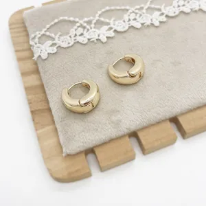 Macro detail of high-quality gold geometric chunky hoop earrings on a soft fabric display