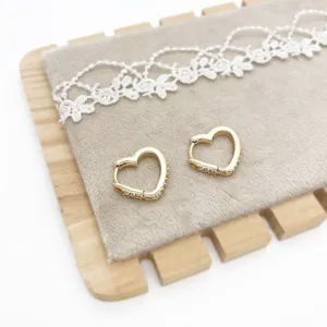 Detailed view of gold heart-shaped huggie earrings with shimmering pavé accents.