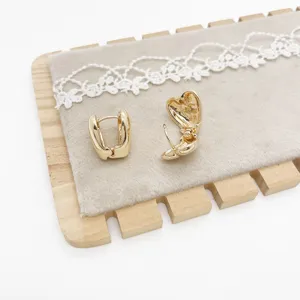 Detailed view of minimalist gold geometric heart-shaped earrings on a velvet stand