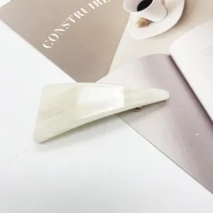 Close-up of elegant triangular resin hair clip with cream marble texture details
