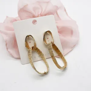 Detail showing the intricate texture of golden geometric linked earrings on a card
