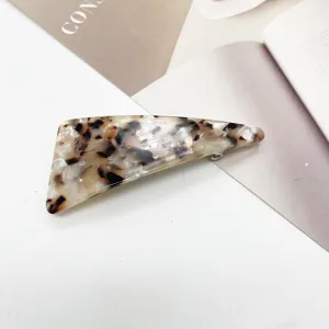 Macro detail of geometric triangular hair clip with elegant marble resin texture