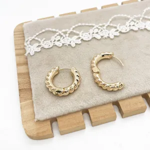 Close-up of gold chunky twisted hoop earrings on a vintage display mat