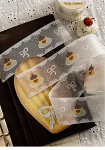 Makro-Detail von Washi-Tape mit Spitzenrand und süßen Pudding- und Schleifenmustern.