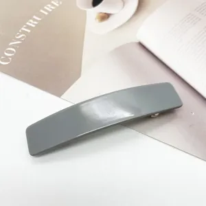 Vue détaillée d'une barrette rectangulaire grise en acétate sur fond esthétique clair