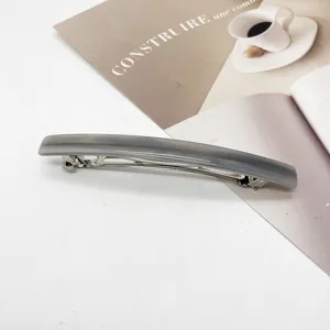 Grey resin rectangular barrette hair clip on a minimalist magazine background