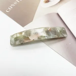 Gros plan d'une pince à cheveux rectangulaire en acétate avec motif de marbre vert