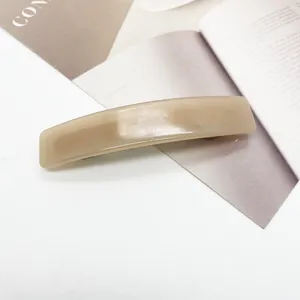 Gros plan sur une pince à cheveux rectangulaire en acétate beige minimaliste sur magazine