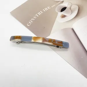 Macro view of minimalist marbled resin rectangular spring barrette for hair styling