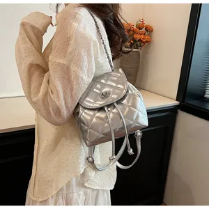Detail eines silbernen gesteppten Rucksacks aus Lackleder mit Drehverschluss und Kette