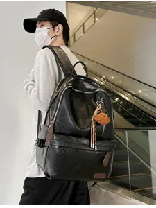 Male model wearing a retro black leather backpack in a stylish modern mall setting