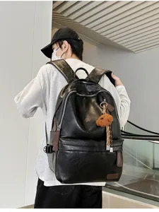 Back view of a man carrying a black vintage soft leather commute backpack with bear charm