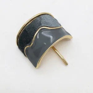 Dettaglio dell'accessorio per capelli a U in velluto grigio e smalto per coda.