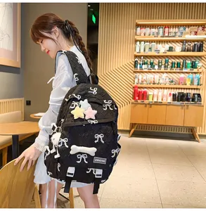 Chica con mochila acolchada negra con bordado de lazos y adornos de estrellas en un café