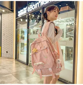 Niña con mochila rosa bordada con lindos colgantes de peluche de estrellas y corazones