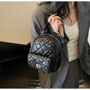 Detail of mini black quilted backpack with rhinestone accents and chain strap