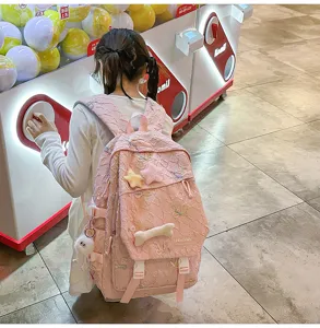 Vista detallada de una mochila escolar rosa con bordado de mariposa en un entorno de estilo vida.