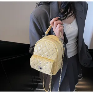 Close-up of yellow quilted mini backpack with rhinestone details and chain strap