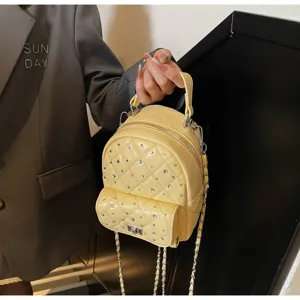 Detail of a mini yellow quilted backpack with silver rhinestones and chain strap