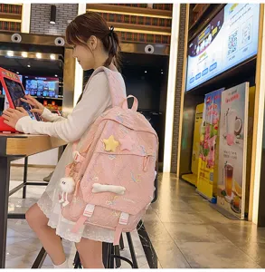 Vista detallada de una linda mochila rosa con lazos bordados y colgantes de estrellas.