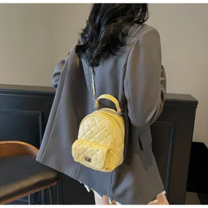 Rear view of model wearing a mini yellow quilted backpack with chain strap