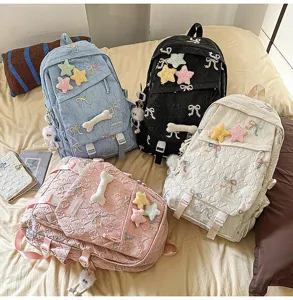 Cuatro coloridas mochilas escolares con bonitos lazos y estrellas mostradas en una cama
