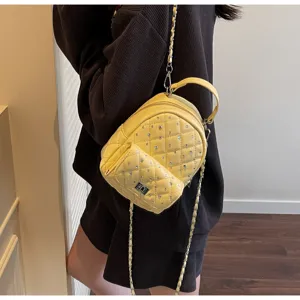 Trendy yellow mini quilted backpack with silver studs and chain strap shown on model