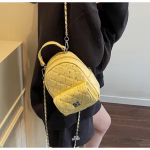 Detail view of yellow mini quilted backpack with chain strap and rhinestones
