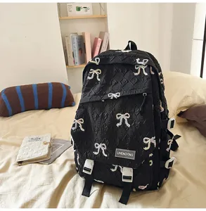 Vista detallada de una mochila acolchada negra con bonitos patrones de lazos bordados a color
