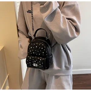 Detail of black mini quilted backpack with rhinestones and silver chain strap