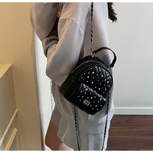 Model wearing a stylish mini black quilted backpack with rhinestones and silver chain strap