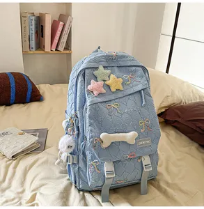 Mochila escolar acolchada azul claro con lazos y estrellas sobre una cama cómoda